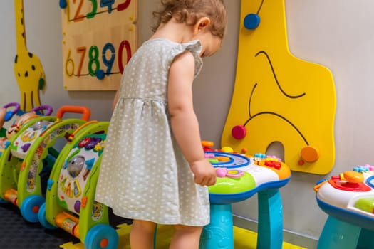 Child interacting with an educational activity table in a colorful playroom, developing motor skills and creativity. Concept of discovery and engaging early education through play