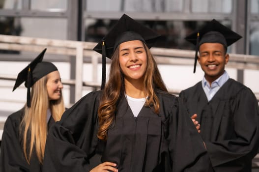 Happy multiethnic graduates wearing their graduation gowns and caps, celebrating their academic achievement