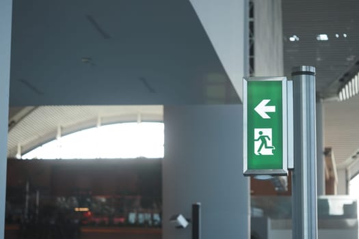 Green exit sign indicating the way to safety in a spacious hallway.