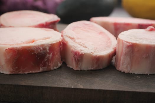 Marrow bones are displayed on a wooden cutting board for preparation.