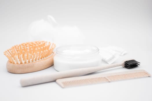 Wooden hairbrush and comb with toothbrush and lotion in minimalist setting.