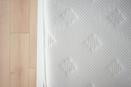 Close view of a mattress placed on a wooden floor of a cozy bedroom.