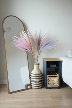 A chic setting showcases a tall mirror with a vase of colorful pampas grass.