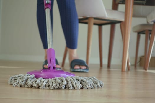 A person mops wooden floors in a stylish living space, maintaining cleanliness.