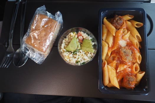 Enjoying a meal with pasta, salad, and dessert while flying high