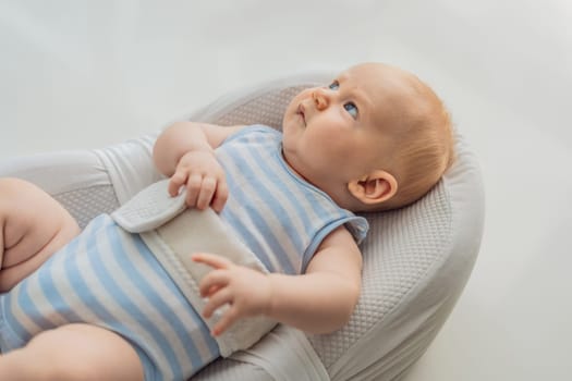 Adorable 3-month-old baby lying safely in a cozy infant cocoon secured with a special safety belt. Comfortable and protective design for newborn care. Parenting, safety, and baby comfort concept.