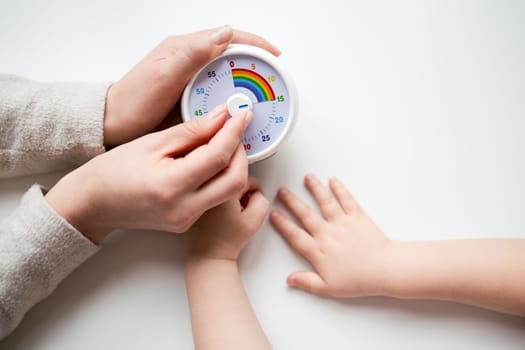 Adult and child hands setting kids timer on white background.