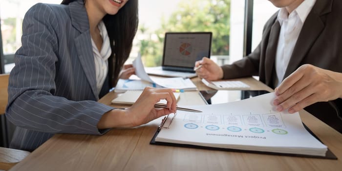 A business team is engaged in analyzing project management documents and discussing strategies while working together at a contemporary office table.