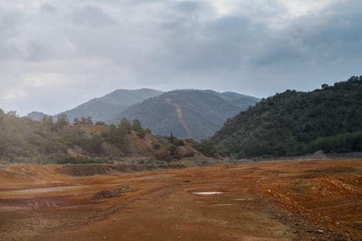Sparse earth lies under a grey sky, with rugged mountains in the distance, setting an atmospheric scene.