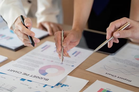Team members are analyzing a budget pie chart and data reports during a meeting, focusing on financial strategies and key insights.