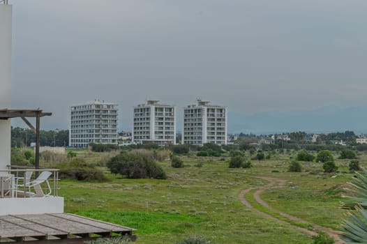 Tall buildings stand prominently in a serene landscape, surrounded by greenery, evoking a peaceful urban oasis.
