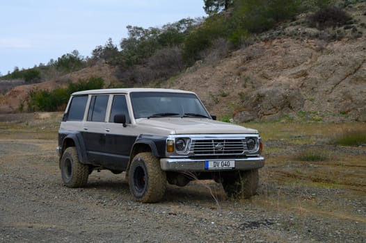 Gaziveren Cyprus -15.02.2025 A vintage SUV navigates rugged terrain, embraced by nature's untamed beauty on a sunny afternoon.