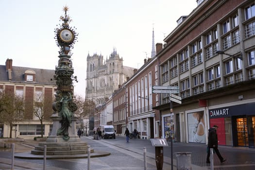 The ornate clock tower stands in the foreground of Amiens. France 17.02.2025, with the majestic Gothic cathedral rising in the background.