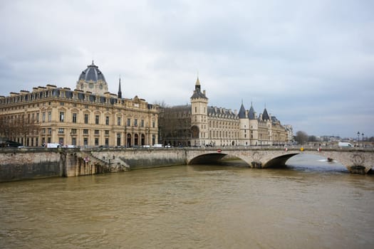 A picturesque view of historic Parisian landmarks along the Seine River, featuring elegant buildings and a classic stone bridge.