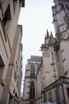 A striking view of modern buildings juxtaposed with the intricate Gothic architecture of Amiens Cathedral in France, showcasing a blend of eras.