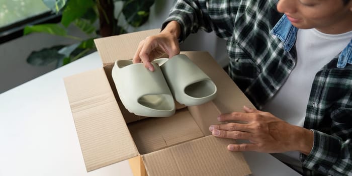A person is unpacking a pair of trendy green slides from a cardboard box, highlighting the excitement of online shopping.