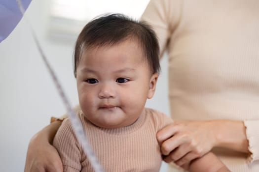 A baby looks curiously as a pediatric doctor interacts with them during a check up, with the parent providing support.