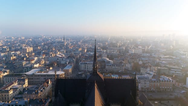 A breathtaking aerial view from Reims Cathedral, showcasing its spire and the sprawling historic cityscape of Reims bathed in sunrise light.