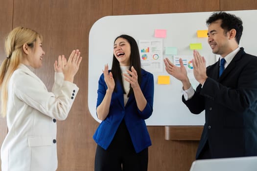 A diverse group of colleagues applauds and celebrates their achievements in a business meeting, promoting a positive work culture.