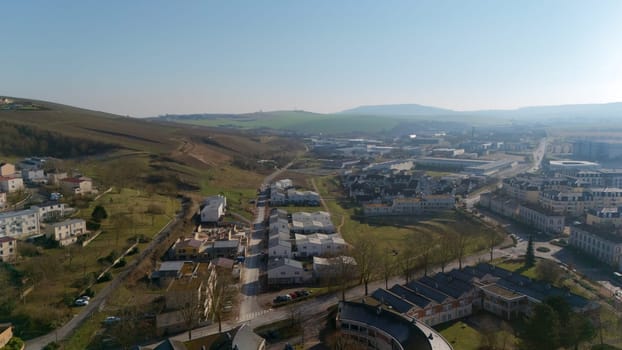 Aerial view of a residential area in Epernay, France, surrounded by green hills, farmland, and industrial zones under a sunny sky.