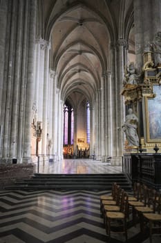 A captivating view inside Cathedral, showcasing vaulted Gothic arches, vibrant stained glass windows, a gilded altarpiece, and intricate stone details. Amiens. France 17.02.2025