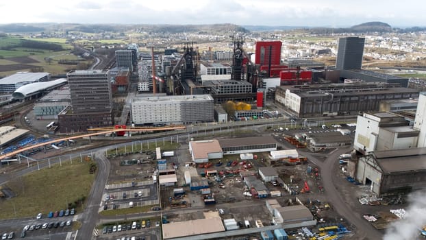 High-angle aerial view of Esch-sur-Alzette, Luxembourg 02.11.2025 showcasing a mix of industrial zones, modern urban developments, historic steel structures, railway infrastructure.