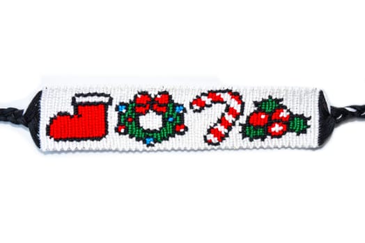 Woven friendship bracelet with pattern Christmas berry, lollipop, wreath and santa boot. Handmade of thread isolaterd on white