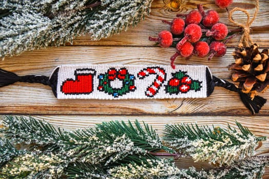 Woven friendship bracelet with pattern Christmas berry, lollipop, wreath and santas boot. DIY New Year gift idea