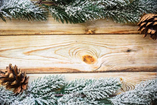 Wooden Christmas background frame with snowy fir tree branches and cones. new year design, copy space