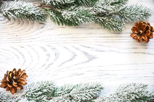 Wooden Christmas background frame with snowy fir tree branches and cones. new year design, copy space