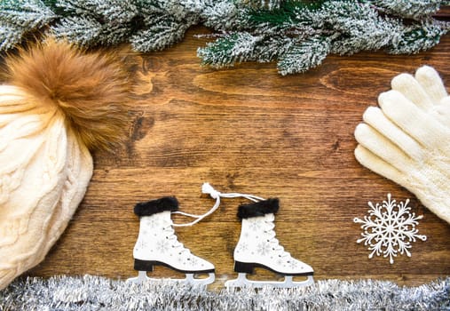 Wooden Christmas tree toy Skates with snowflakes, tied with rope, on white tinsel imitating ice. Snowy 
fir branches from above. Wooden background with copy space. Creative New Year composition.