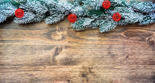 Wooden Christmas background frame with snowy fir tree branches and red balls. new year design, copy space