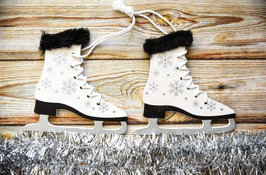 Wooden Christmas tree toy Skates with snowflakes, tied with rope, on white tinsel imitating ice. Wooden background. Creative  New Year composition.