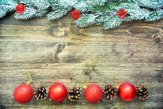 Wooden background frame with snowy fir tree branches, red Christmas tree toys and fir cones. new year design, copy space