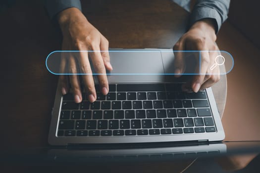 Businessman's hand typing on laptop, searching and browsing the internet for information using a blank search bar. Search engine optimization and networking concept is depicted.