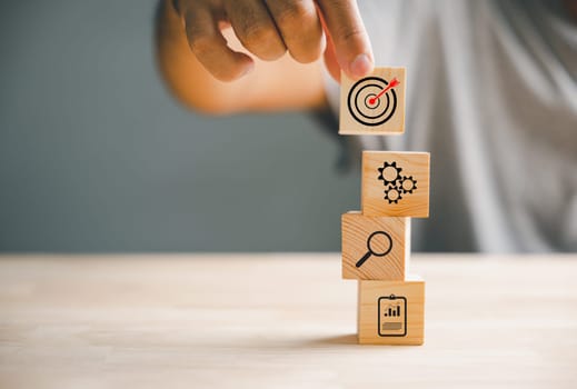 Businessman's hand arranging wood blocks with precision, depicting a business strategy and Action plan. This image represents the concept of business development and success.