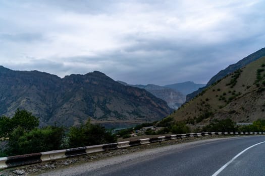 A mountain range is visible in the distance, with a road running through it. The sky is cloudy, giving the scene a somewhat somber mood