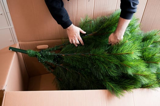 Adult caucasian male assembling artificial Christmas tree from cardboard box.