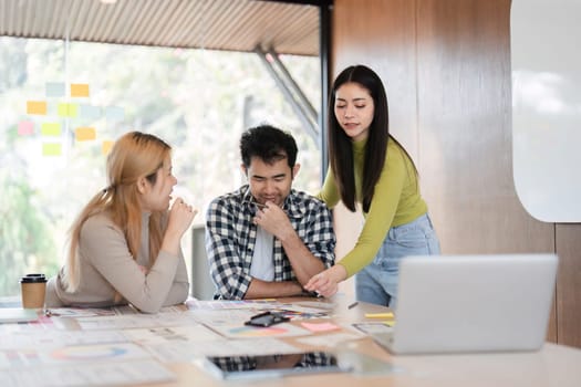 A diverse team collaborating on design strategies, discussing ideas and reviewing materials at a table in a bright office environment.