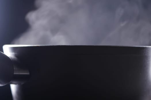 Steam billows from a black pot, indicating hot food being prepared.