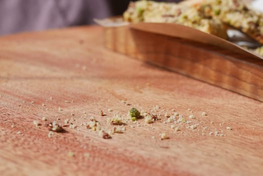 Crumbs are left behind on a wooden surface after enjoying a treat.