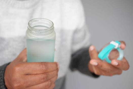 Person holds a glass jar filled with clear water and a lid in hand.