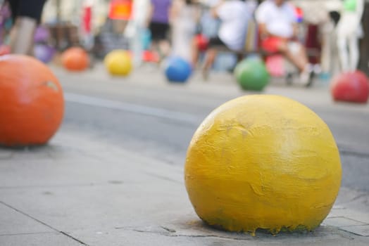 Brightly colored balls are spread across the pavement in a lively urban setting.