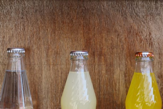 Three distinctive beverage bottles stand aligned on a wooden surface.