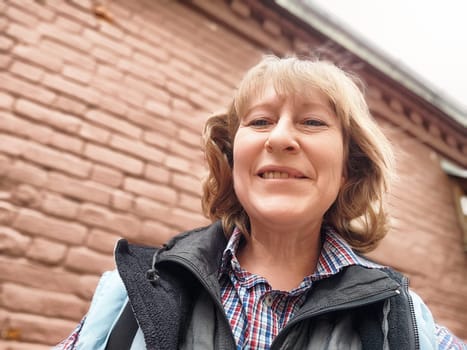 A middle-aged female traveler blogger captures a cheerful selfie during her adventure in a charming destination.