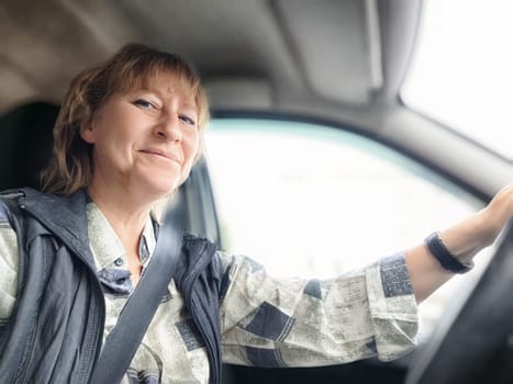 A middle-aged woman enjoys driving while embarking on a travel excursion.