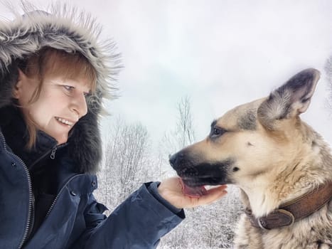 Blogger takes a cheerful selfie with her German shepherd while exploring the winter wonderland during a camping adventure.