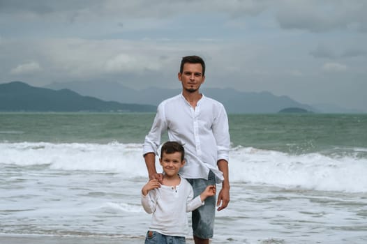 happy father dad with a child boy son on the beach by the sea on a summer vacation