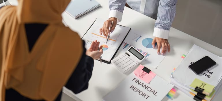 Two women in business attire engage in a discussion about financial reports, showcasing collaboration and professionalism.