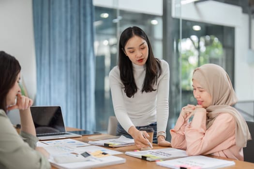 Three women collaborate in a modern office, exchanging ideas and strategies during a dynamic meeting.